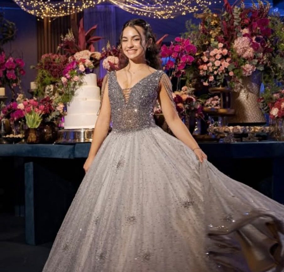 Catarina girando o vestido de cristais em frente à mesa do bolo