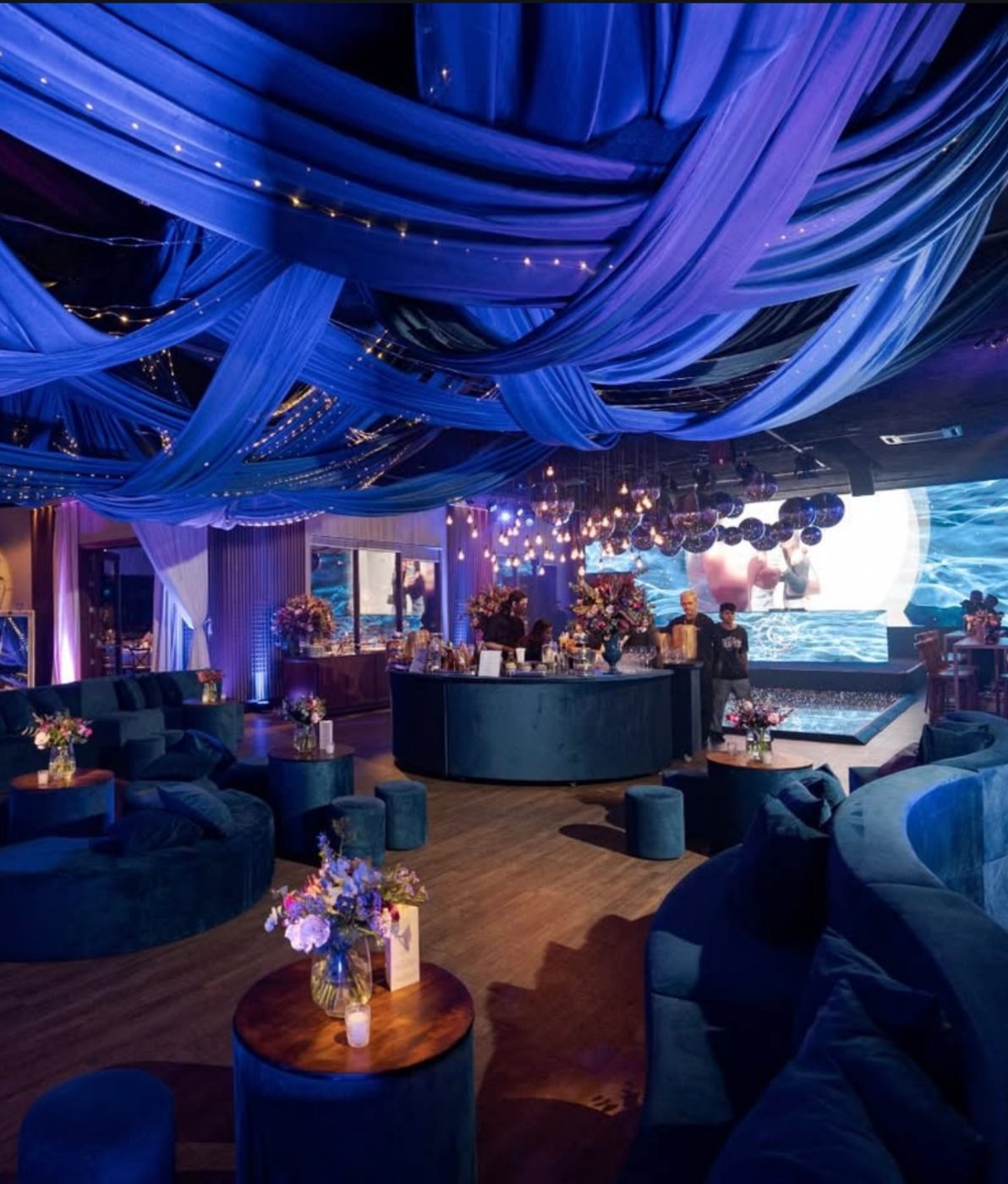 Lounge em veludo azul com teto de tecidos e luzes no Bisutti Traffô