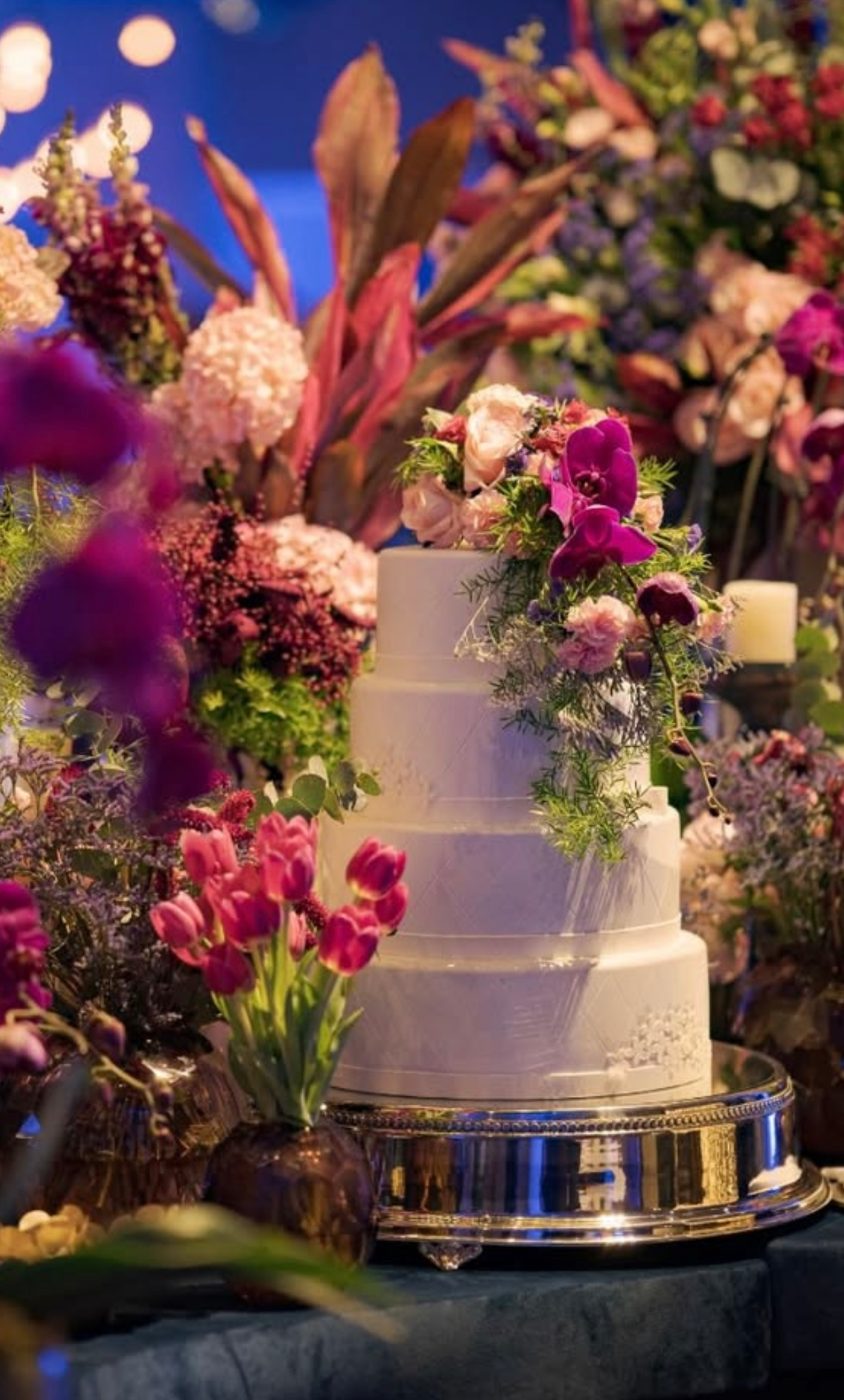 Bolo branco de quatro andares com orquídeas e flores em tons de pink