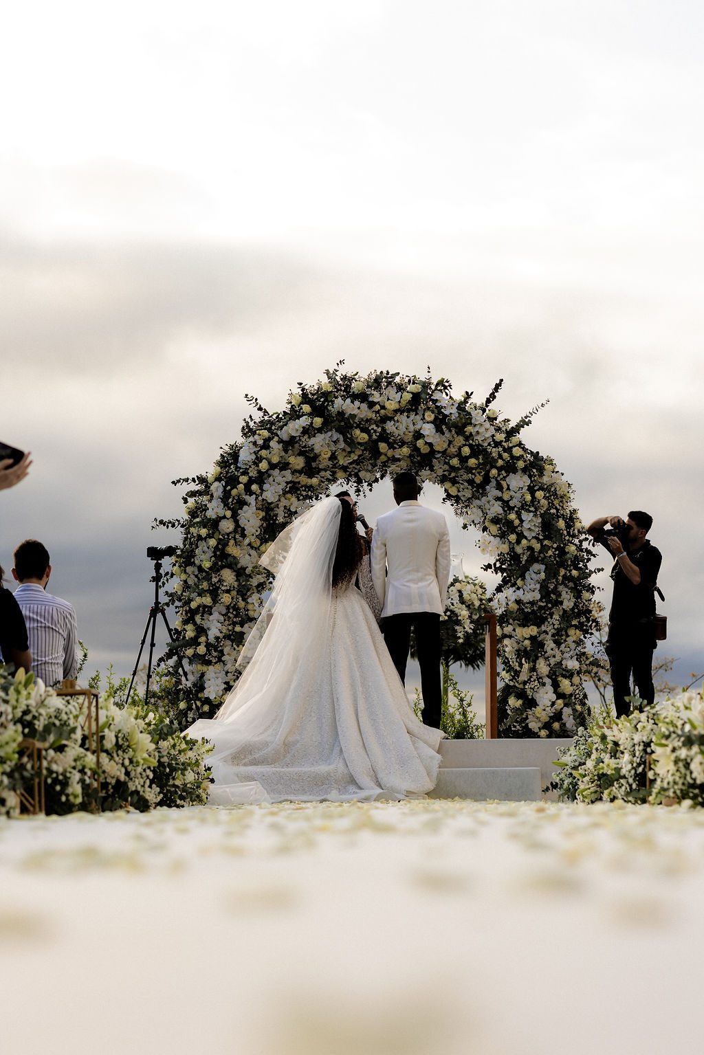 Noivos sob o arco de flores brancas da cerimônia