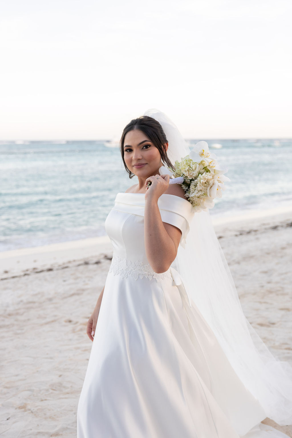 Nathália na praia de Punta Cana com o buquê de flores brancas