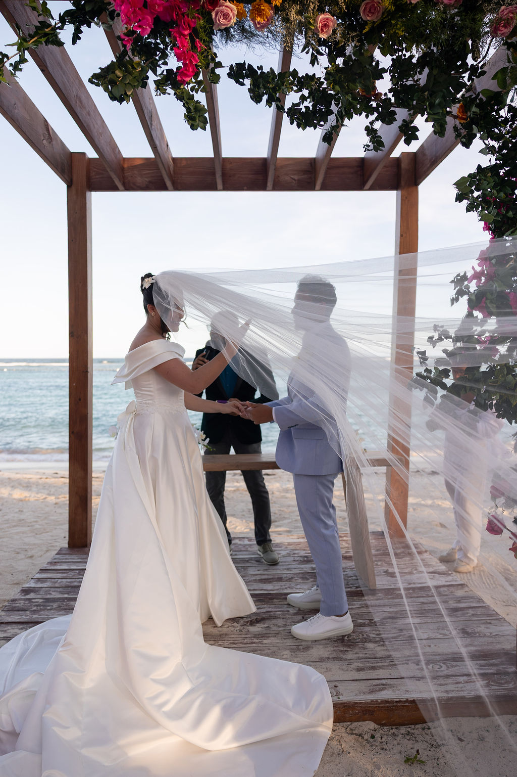 Nathália e Antonio no altar com o véu ao vento e o mar ao fundo